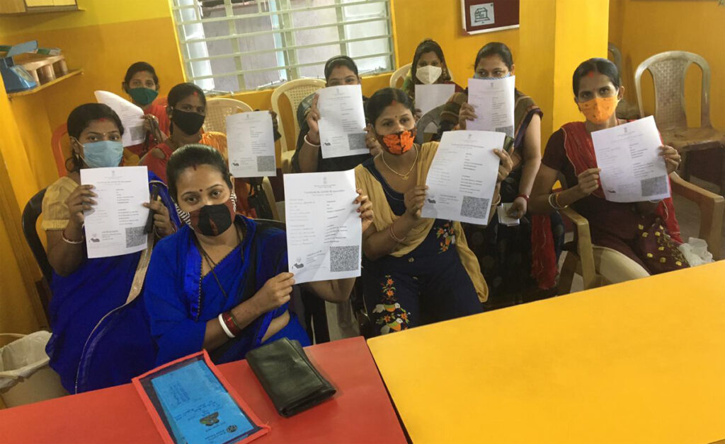 Beneficiaries holding up their government-issued proof of vaccination